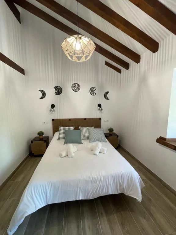 Un dormitorio con una gran cama blanca y una lámpara de araña. en Cabaña Los Tejos,